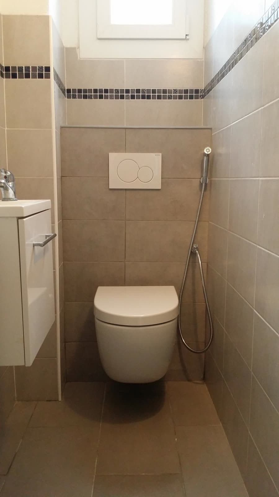 WC installé dans une salle d’eau carrelée avec barre d’appui