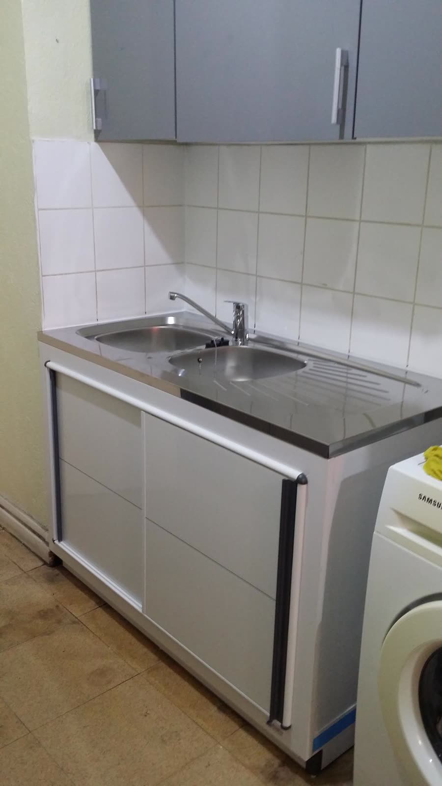 Évier inox et robinet installés dans une cuisine avec lave-linge