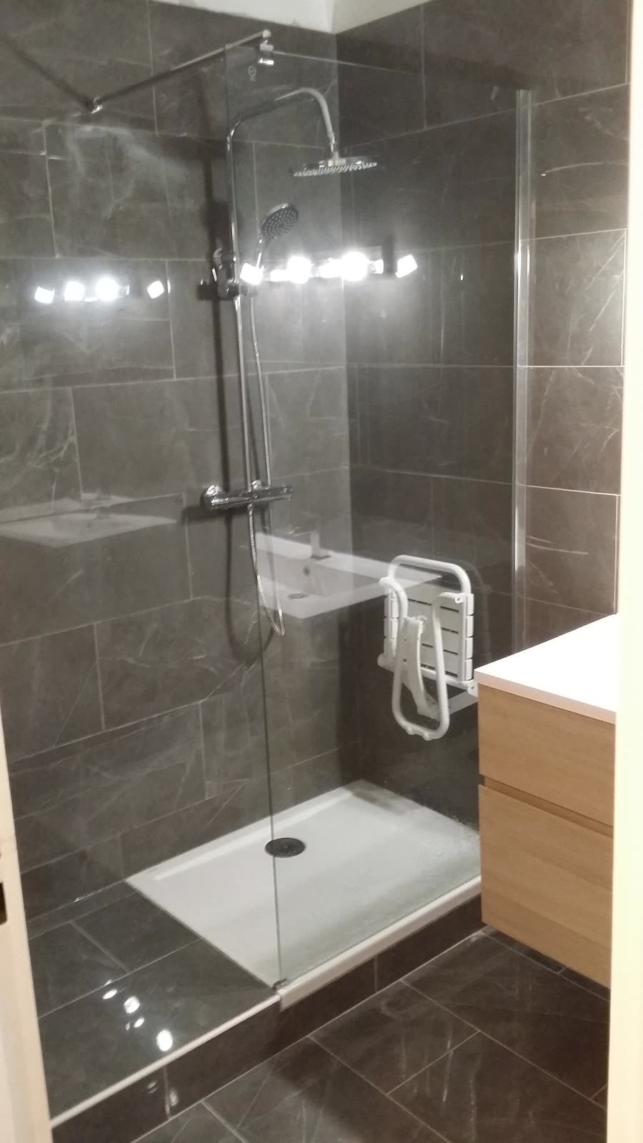Douche avec paroi vitrée et robinetterie, dans une salle de bain rénovée