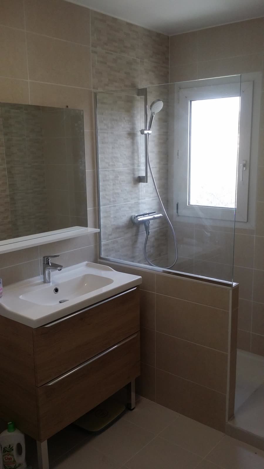 Meuble vasque et douche installés dans une salle de bain carrelée